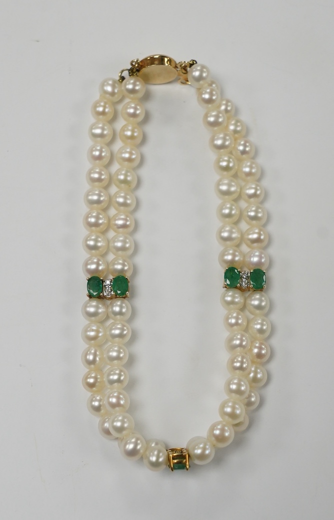 A modern Mexican double strand cultured pearl bracelet, with 14k clasp and emerald and three emerald and diamond cluster set spacers, 17cm. Fair condition.